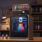 Apex Pro Color 3D printer on a wooden workbench in an evening maker space with printed figures and calipers