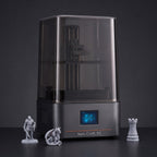 Aura One resin 3D printer with detailed gray resin miniatures: a knight, a dragon and a chess rook