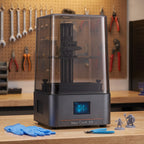 Aura One resin 3D printer on a workshop bench with nitrile gloves, flush cutters and resin miniatures