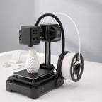 NeoCraft+ mini 3D printer with small white printed objects: a phone stand, a cable clip and a key tag