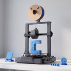 Nova X3 3D printer with blue printed functional parts: a phone stand, a cable clip and gears