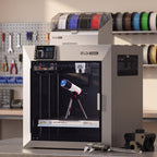 Titan Max Color 3D printer on a steel workbench in a maker workshop with calipers and a printed engineering part